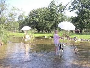 carol with her easel set up in the river
